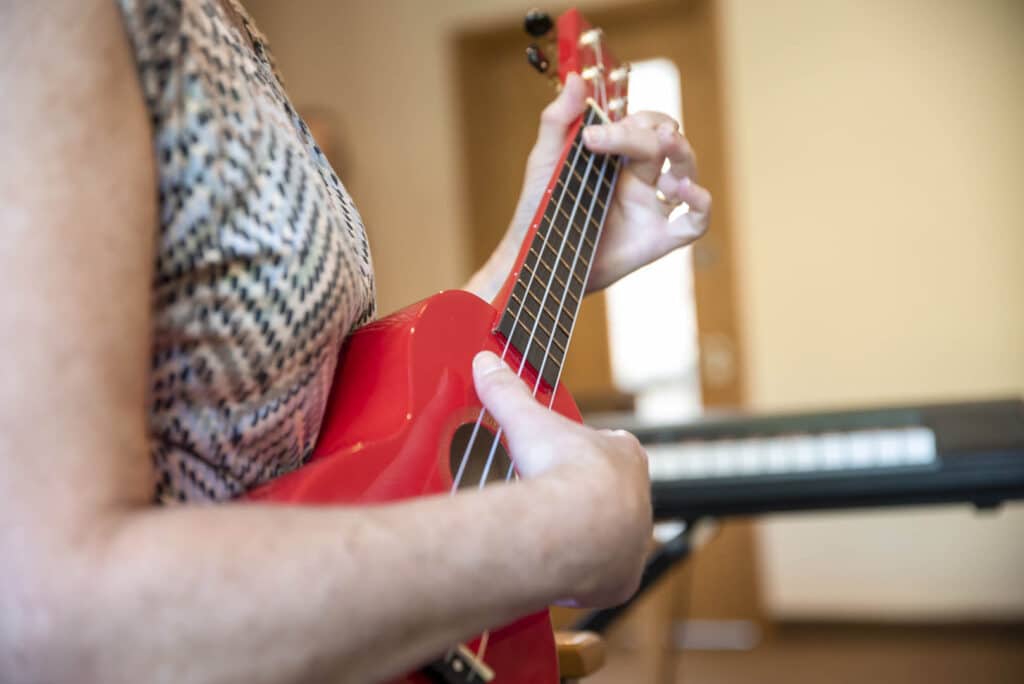 A person holds onto a brightly-coloured ukulele, as they play a song during a music therapy session