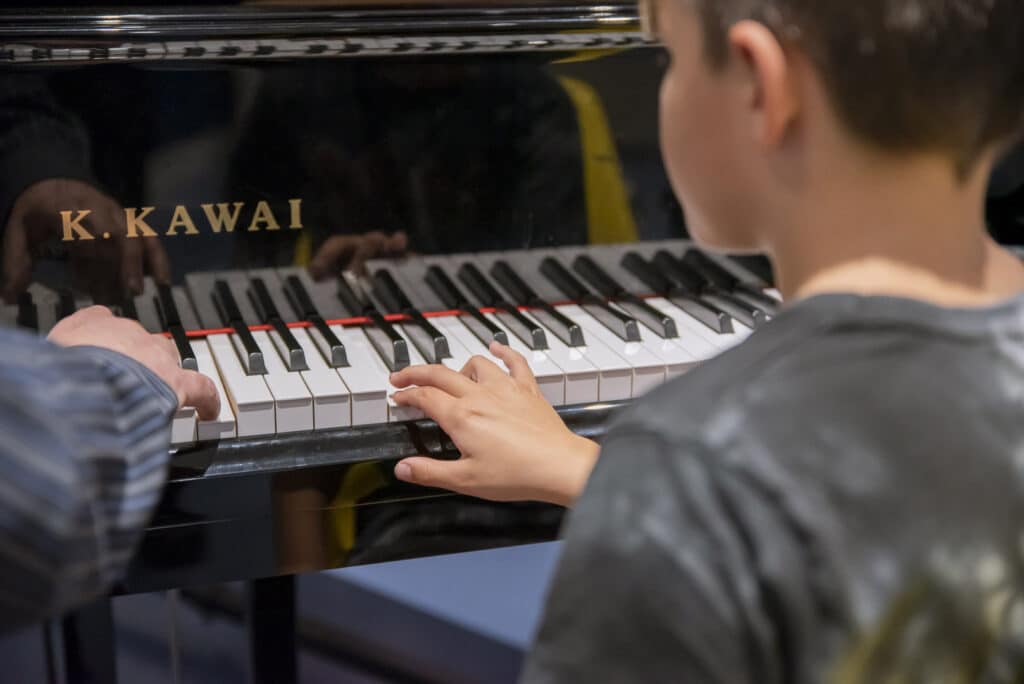 A young client sits down to play music on the piano as they take part in music therapy at one of our partner organisations