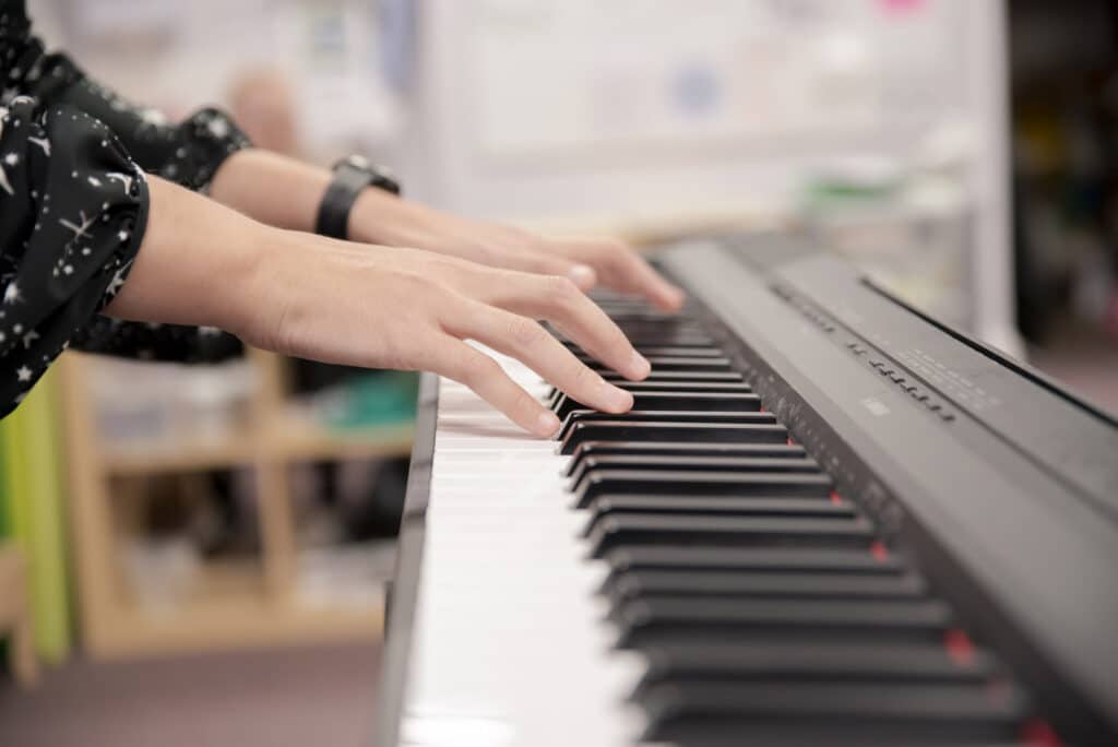 A set of hands play music on a keyboard, as a music therapy session takes place at a Nordoff and Robbins partner school