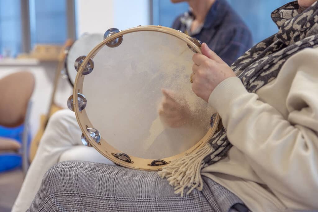 Someone plays music on a tambourine, during a group music therapy session at one of our partner organisations.
