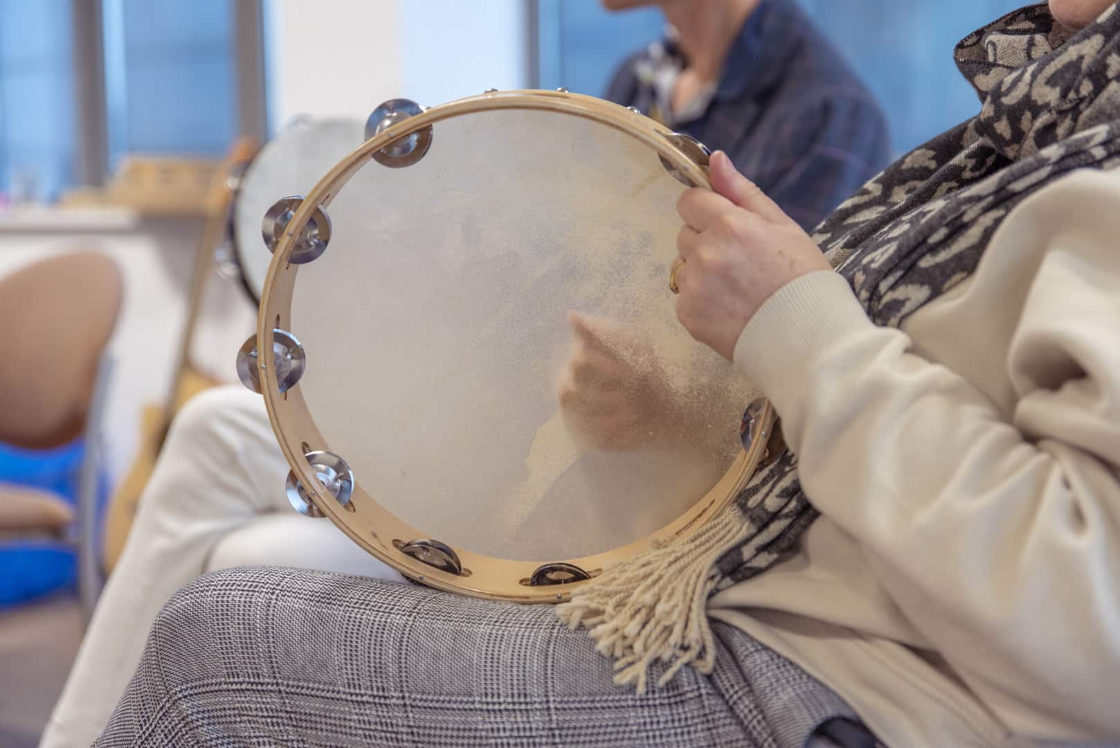 Someone plays music on a tambourine, during a group music therapy session at one of our partner organisations.