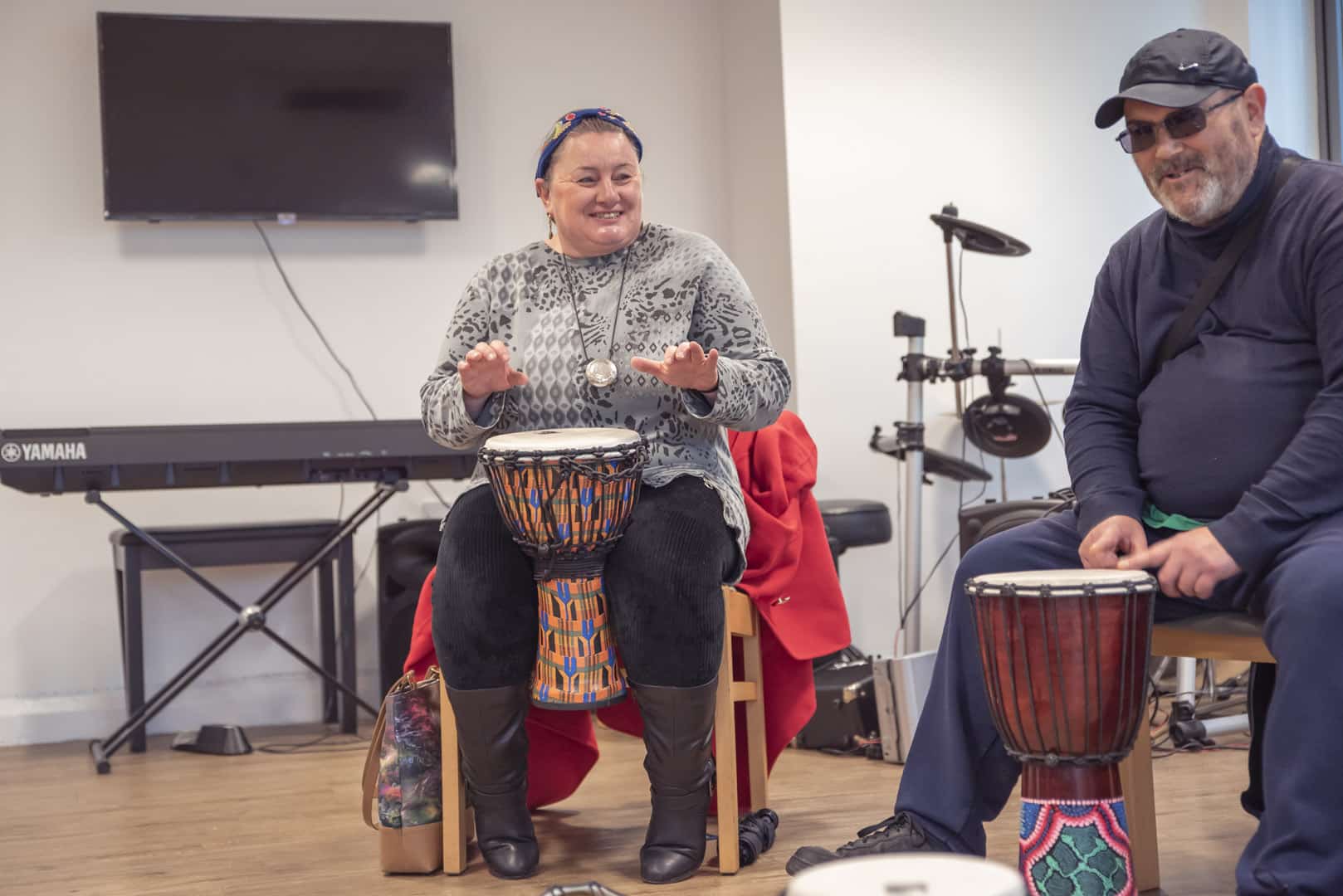 During a music therapy session at partner organisation ReCoCo, two people excitedly play music on the drums