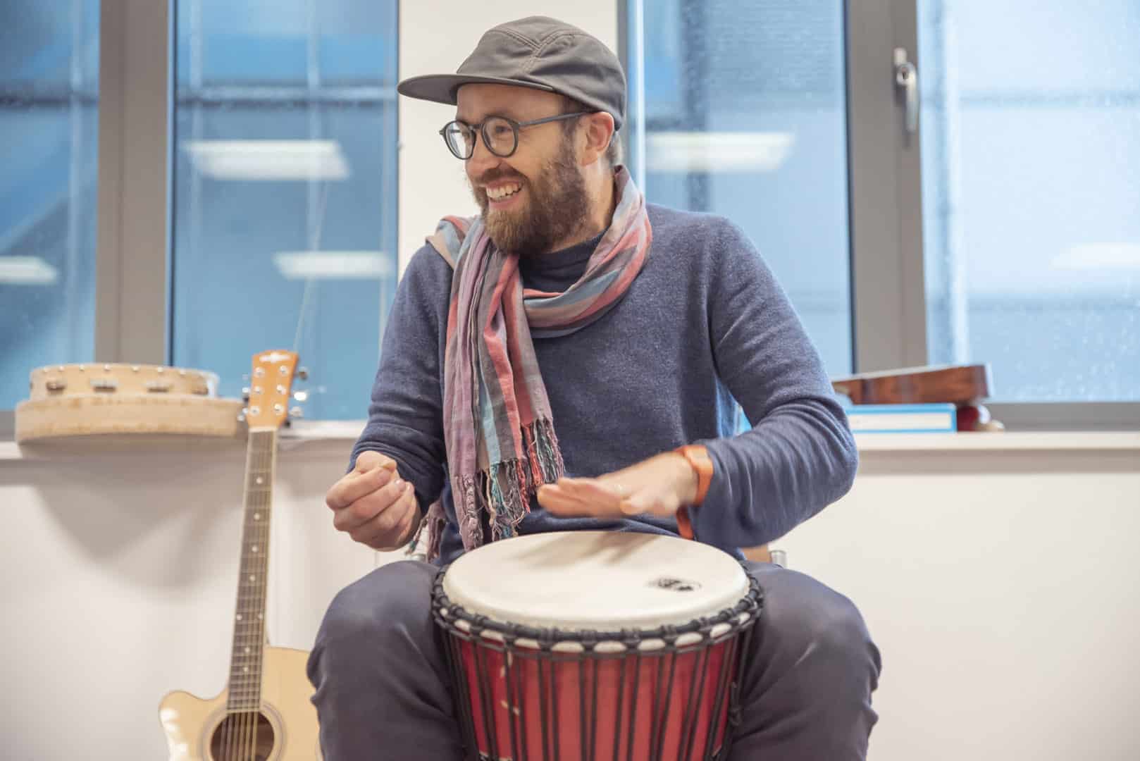 Nordoff and Robbins music therapist Paddy excitedly plays the drums during a music therapy session at ReCoCo, one of our partner organisations in Newcastle.