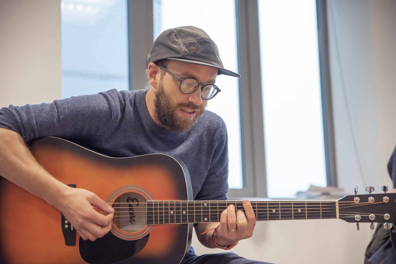 At partner organisation ReCoCo, music therapist Paddy is focussed as he plays the acoustic guitar during a music therapy session.
