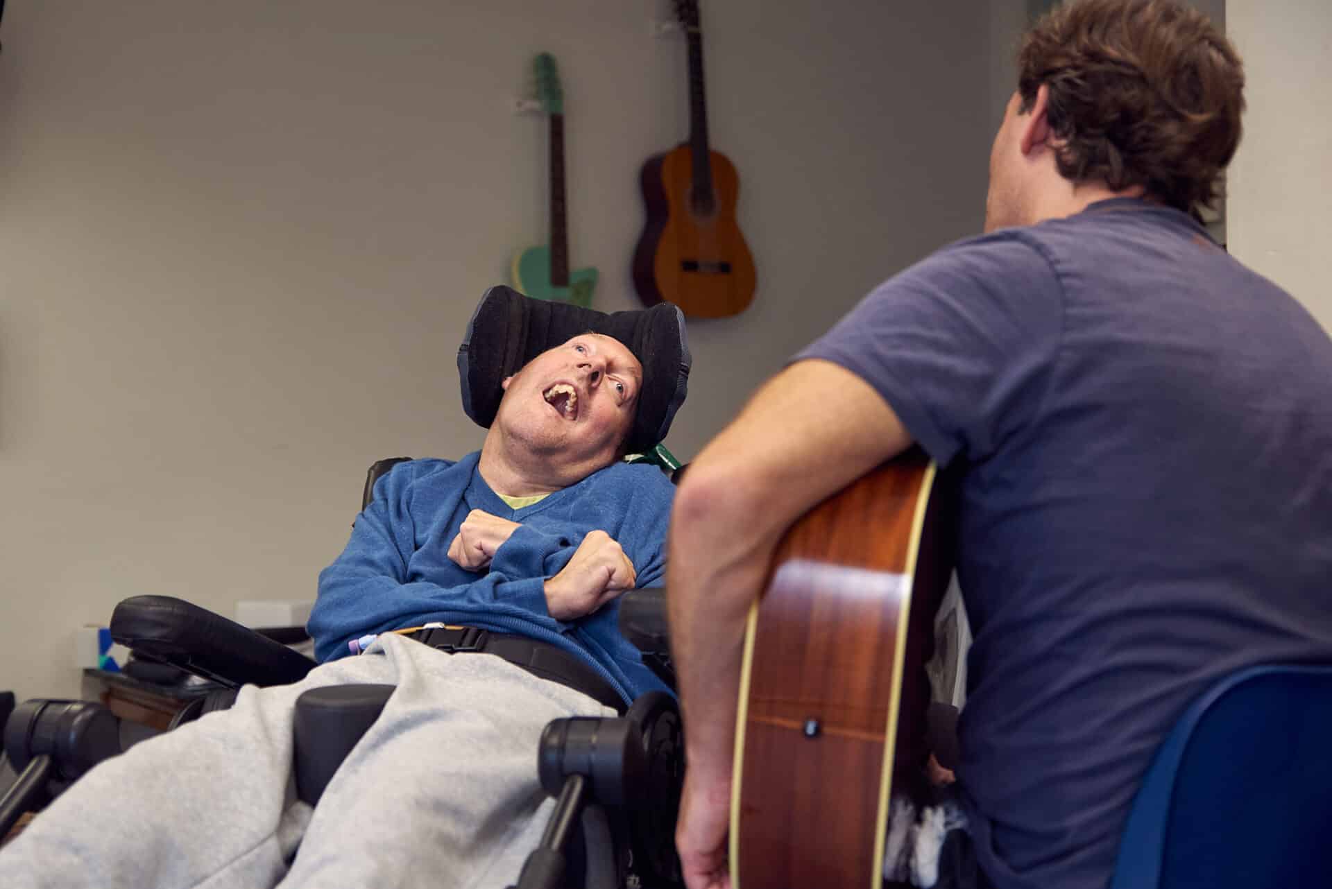 At partner organisation Headway, a client happily looks to music therapist Oli, who plays the acoustic guitar.
