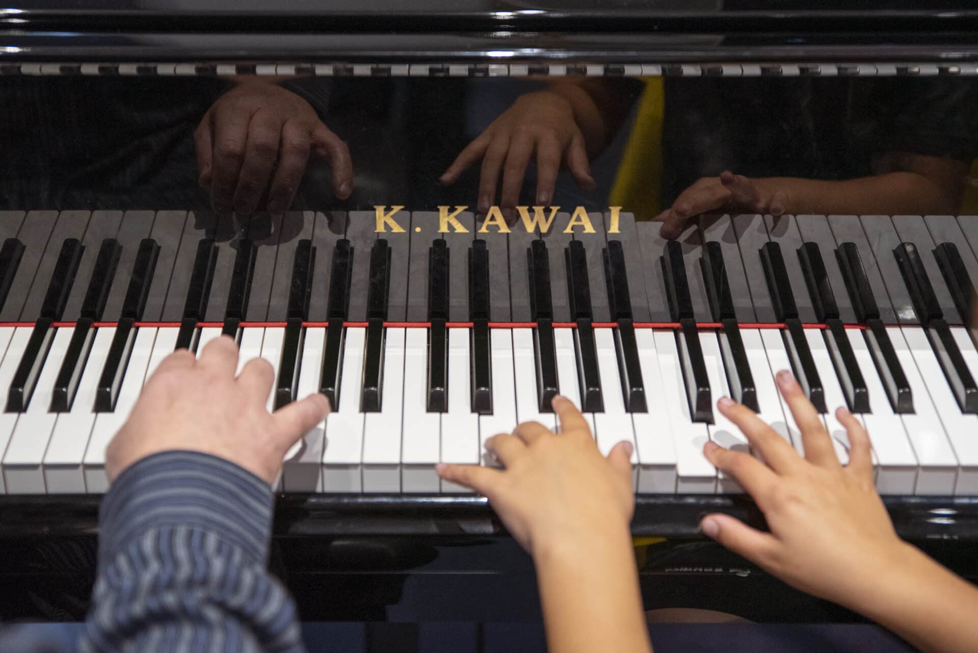 A young client and music therapist sit together at a piano, playing music together during music therapy.