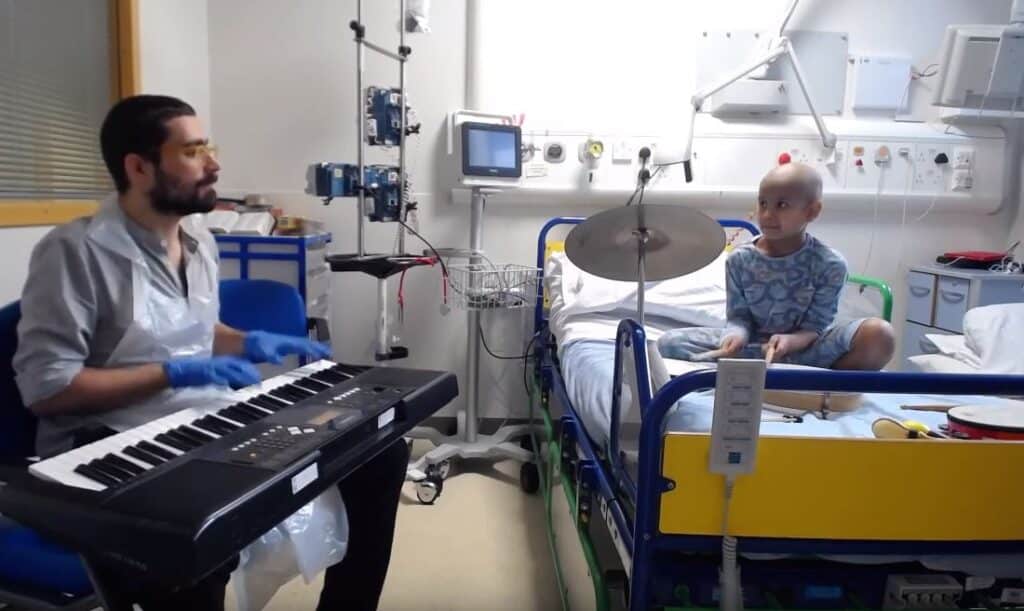 Jonathan plays the symbols sitting in his bed in hospital, as music therapist Jose plays the keyboard.