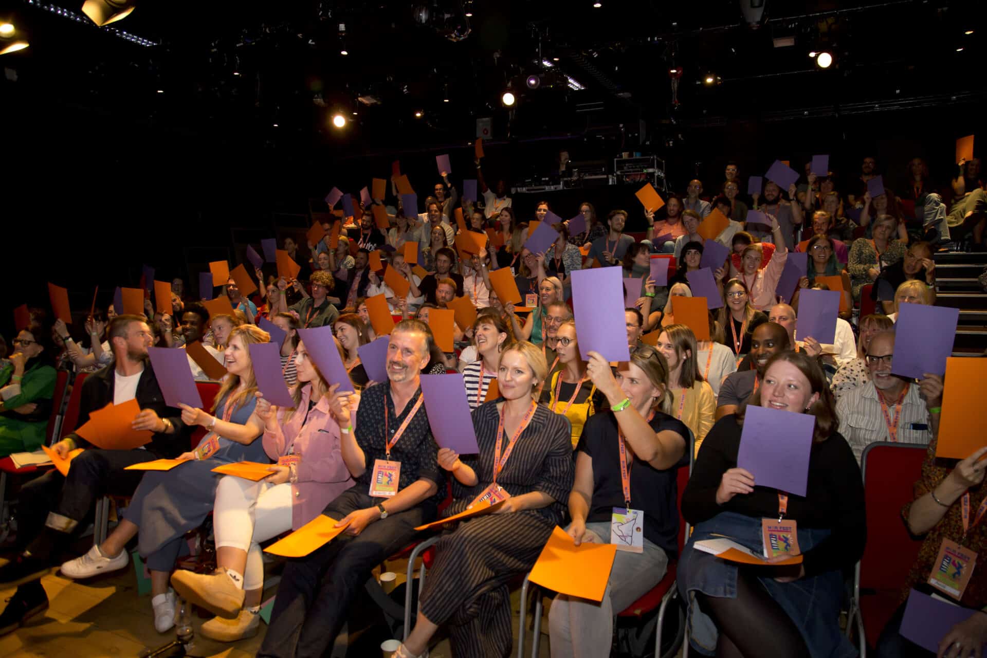 Nordoff and Robbins staff members gather together in an assembly hall, each holding up coloured cards during a group activity.