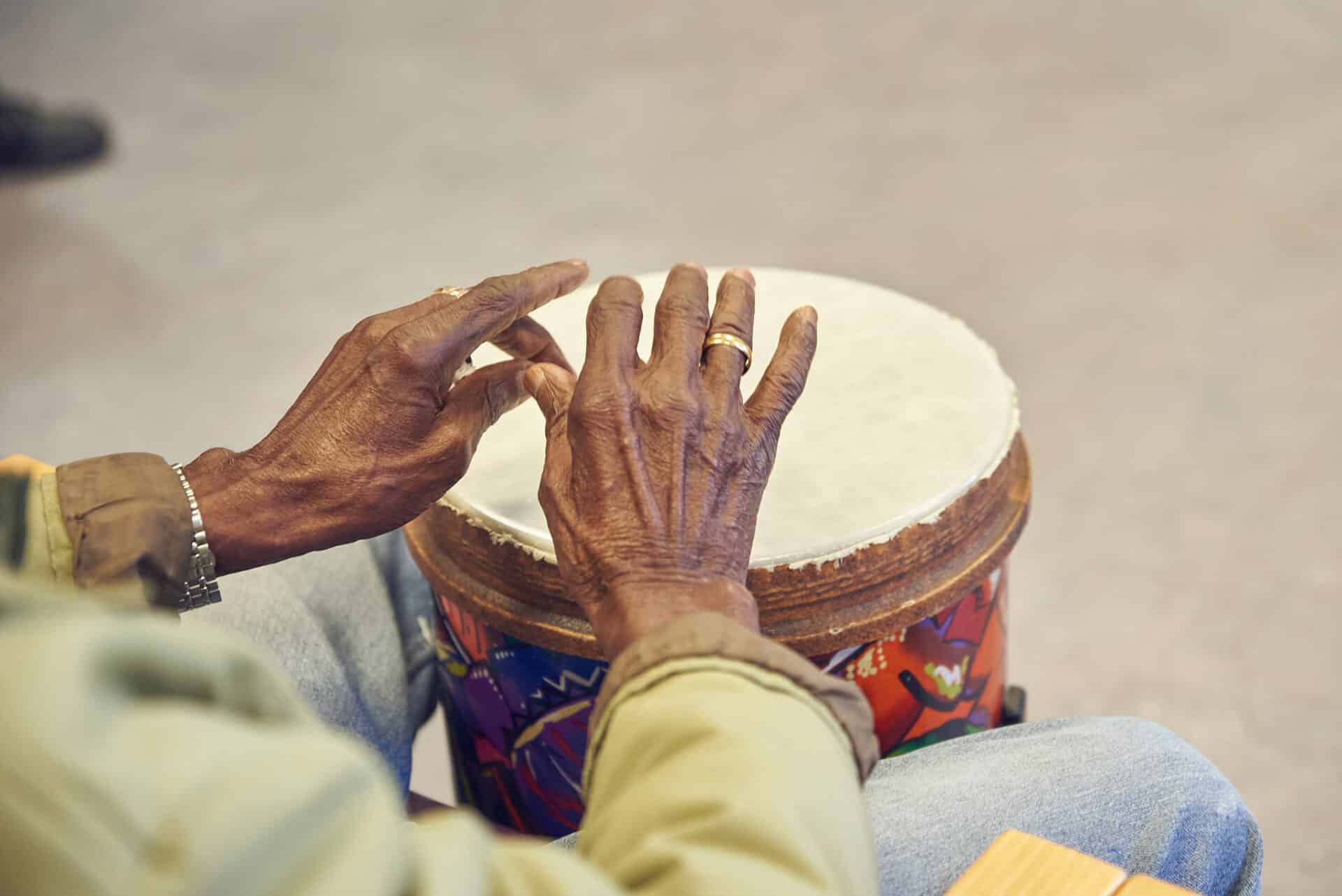 The hands of a client play the drums during a music therapy session at NELFT Memory Clinic, one of our partner organisations.