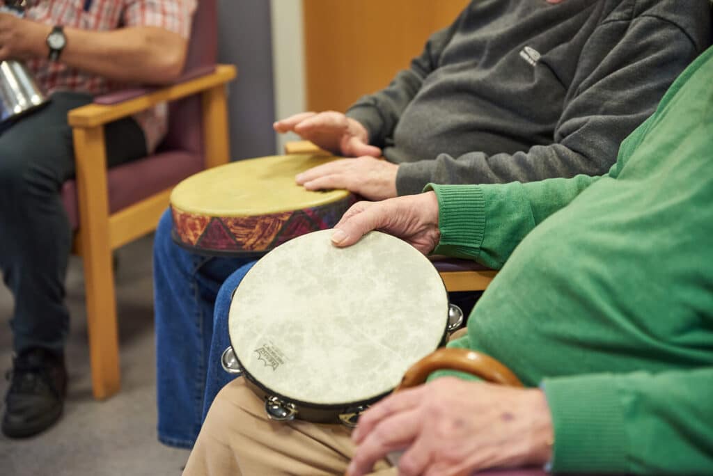 Two people play the drum and tambourine during a music therapy session at NELFT Memory Clinic, one of our partner organisations.