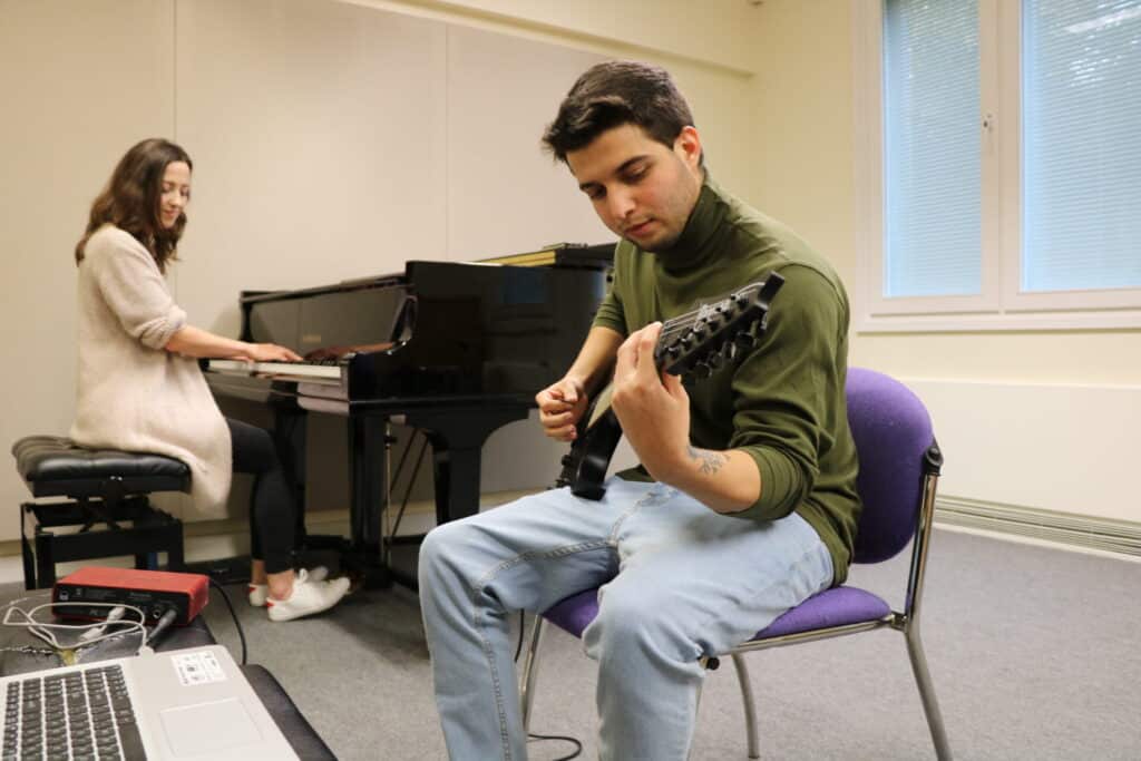 Ali is focused during a music therapy session, as he sits to play the guitar. Music therapist Kerry plays the piano.