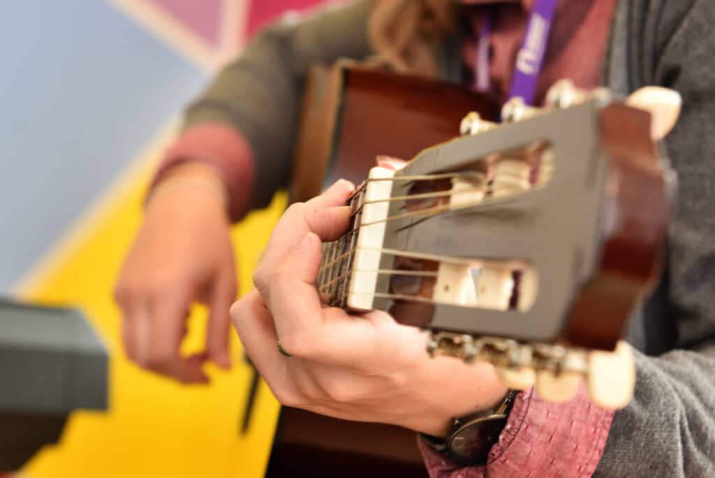 A close up shot of a guitar, held and played by one of our music therapists.