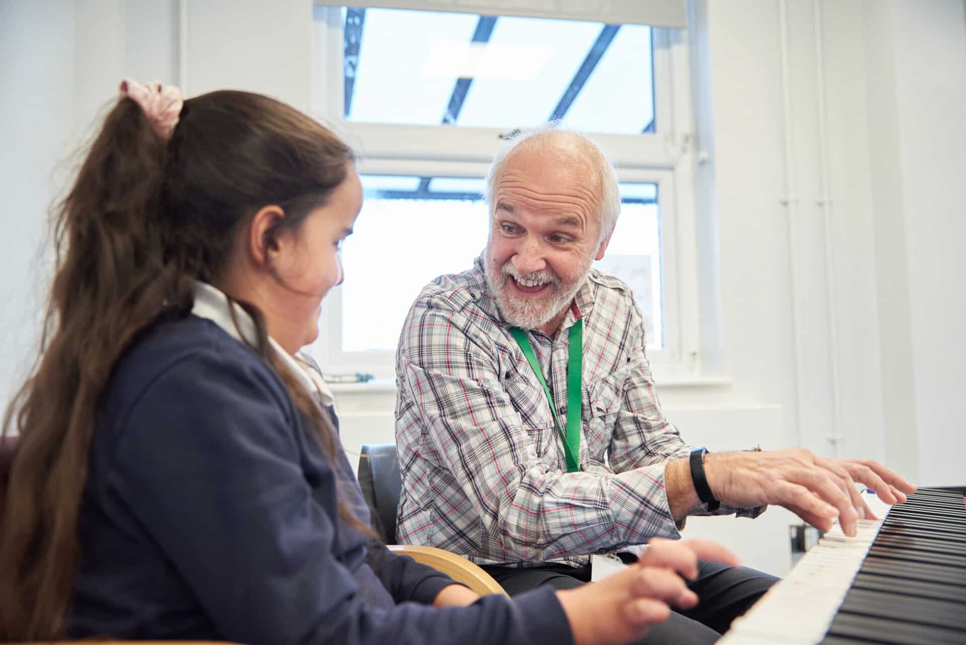 A music therapist smiles encouragingly at a child client as they play an electronic keyboard together.