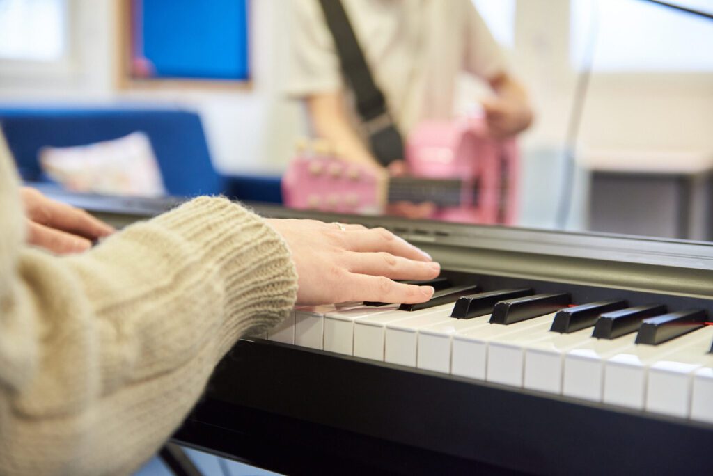 A person runs their hands over the keys of an electric keyboard.