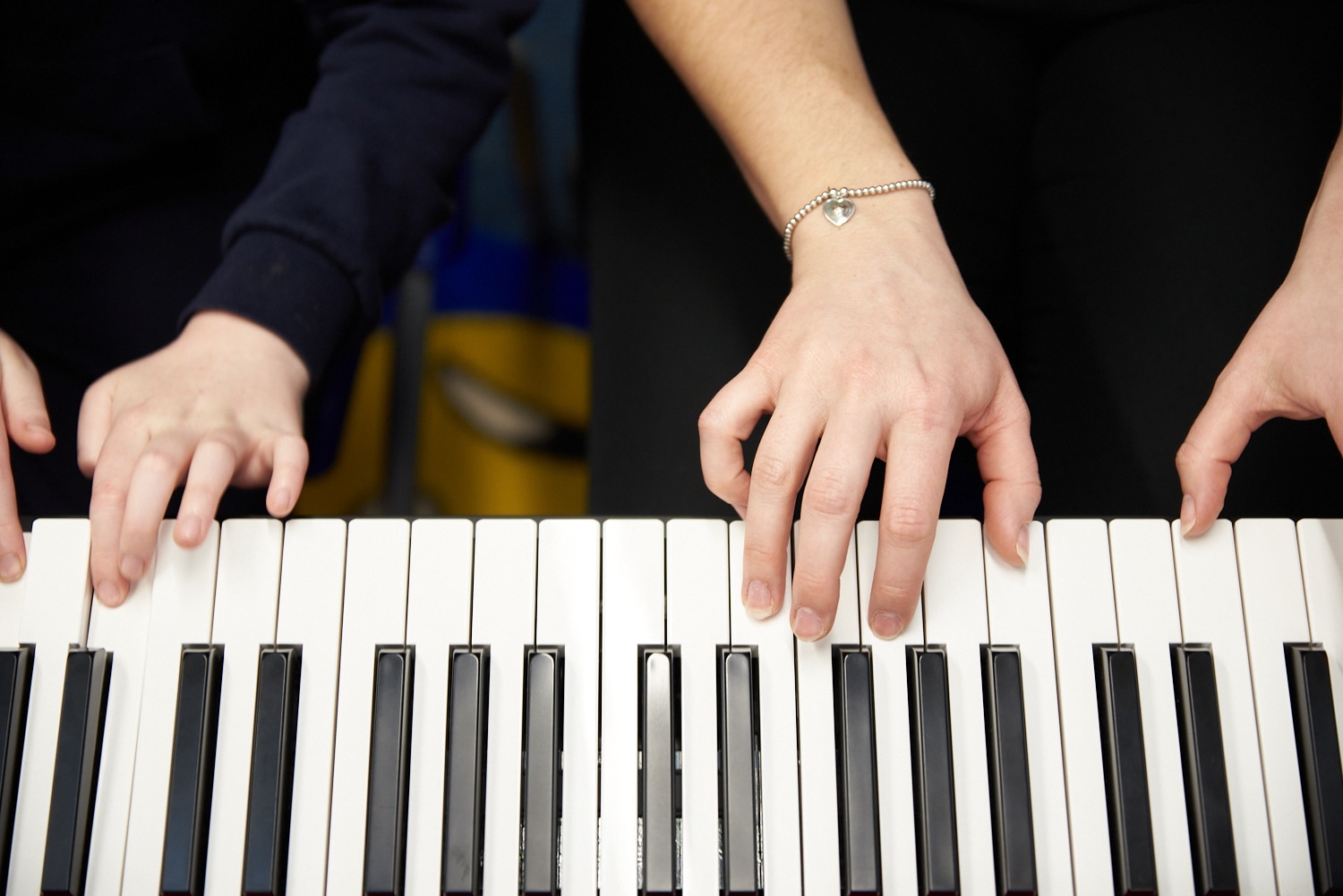Two pairs of hands play the keyboard during a music therapy session