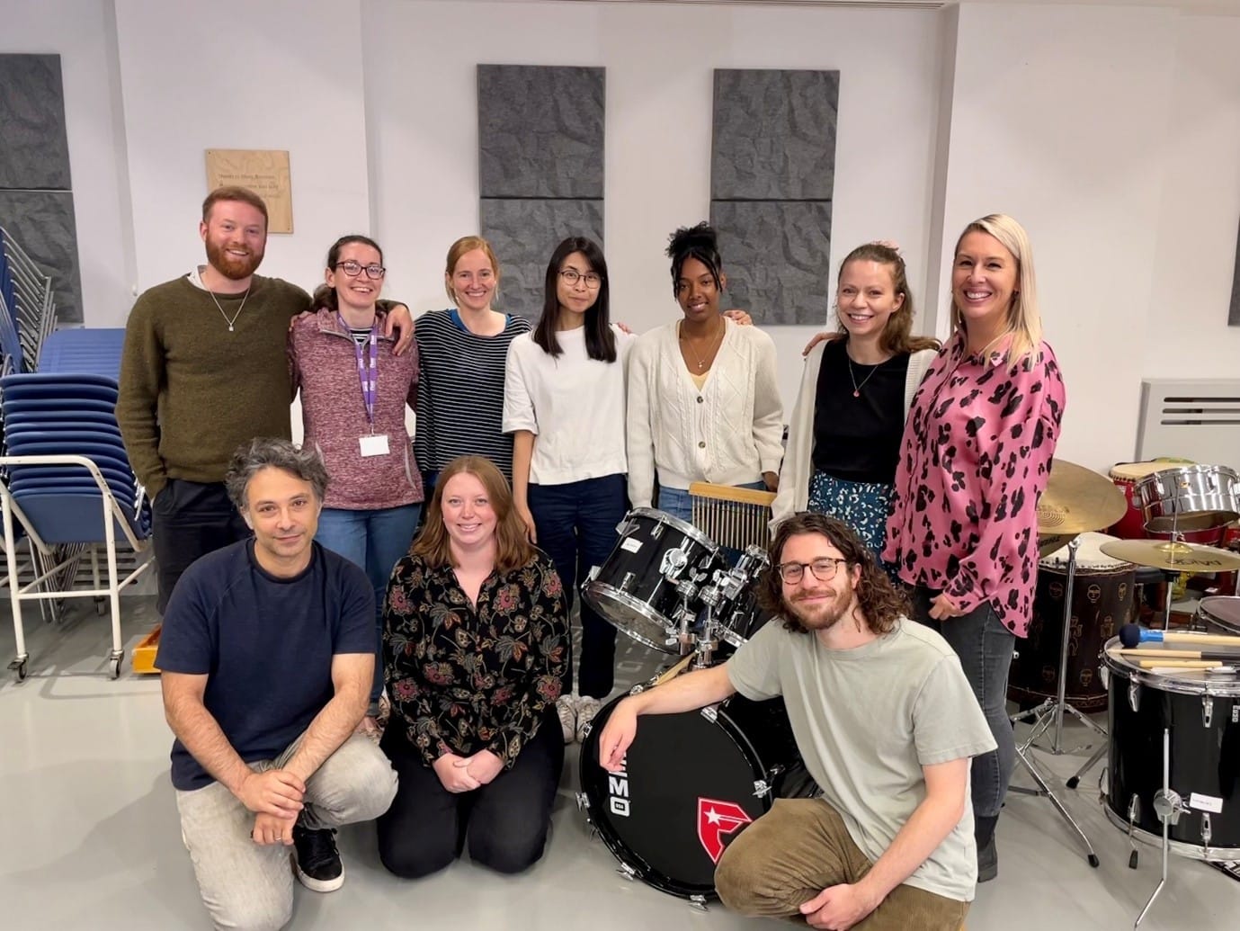 Our Nordoff and Robbins MMT students smile together amongst musical instruments.