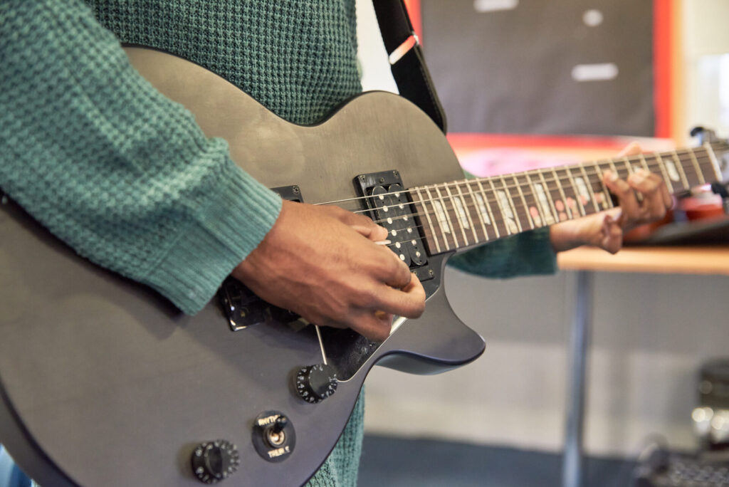 During music therapy, a pair of hands holds up and play an electric guitar.