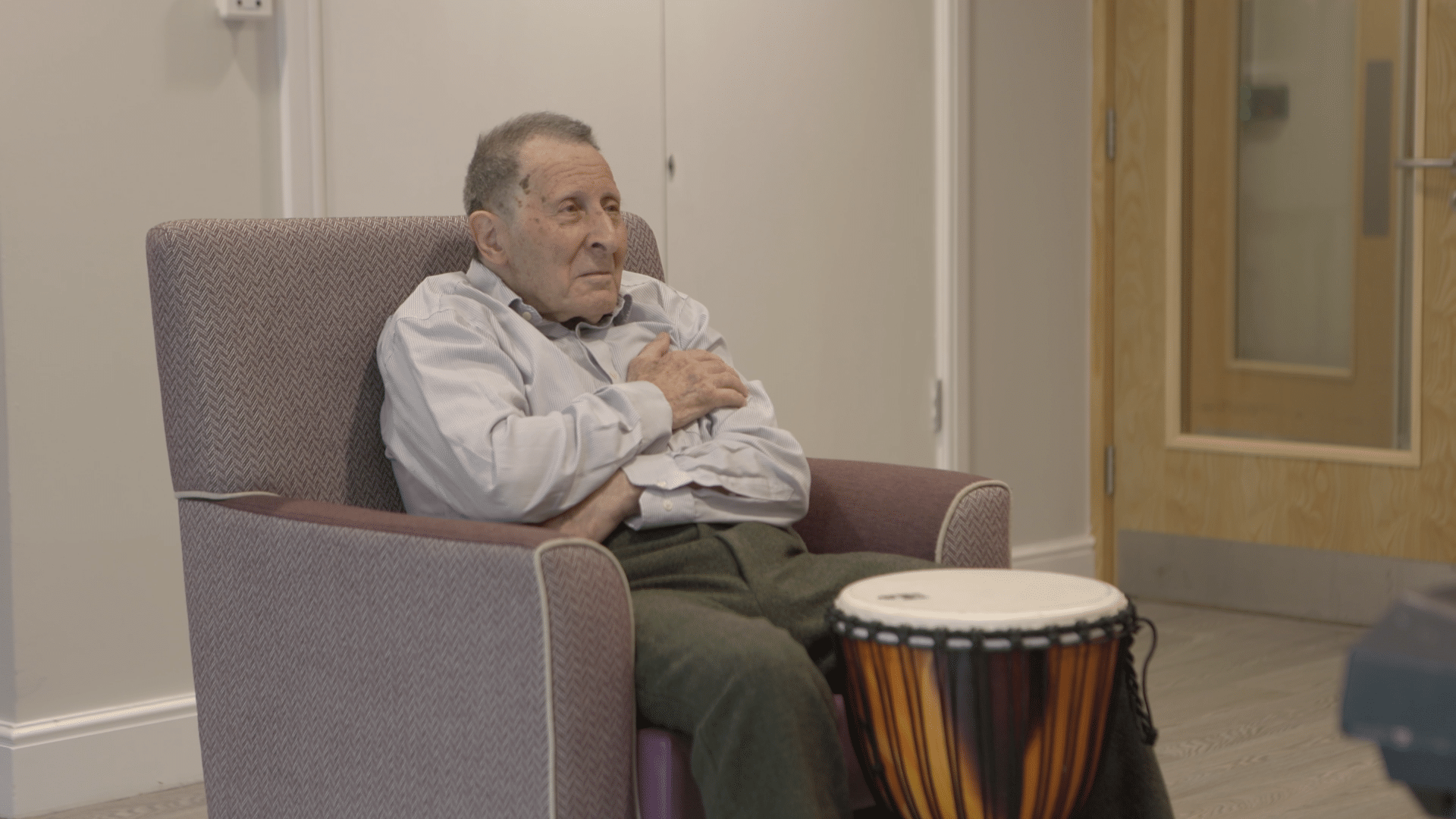 Stephen sits behind a drum during a music therapy session with Kate