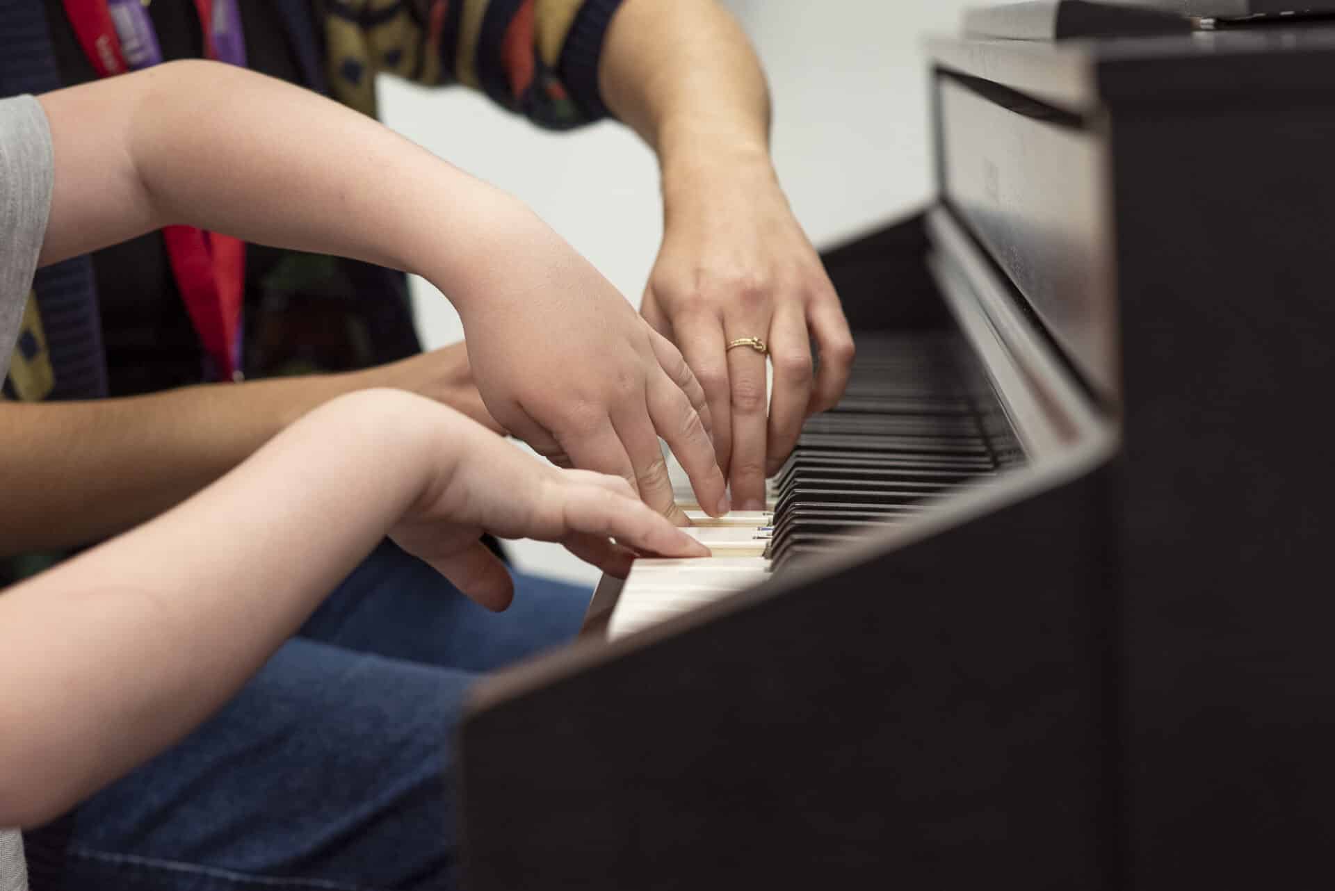 A pupil at one of partner schools and a Nordoff and Robbins music therapist play the piano together