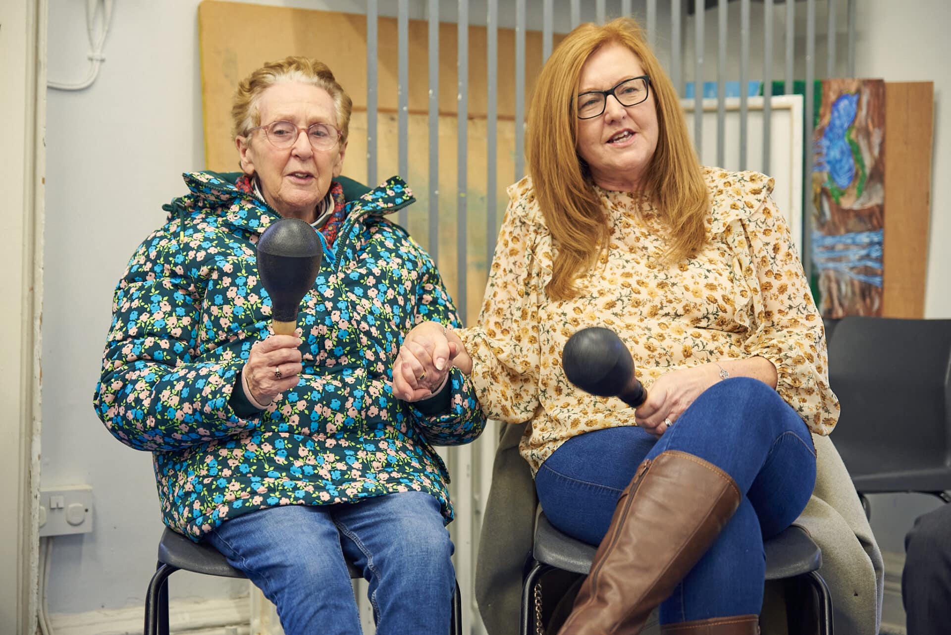 Two women playing musical instruments together and holding hands