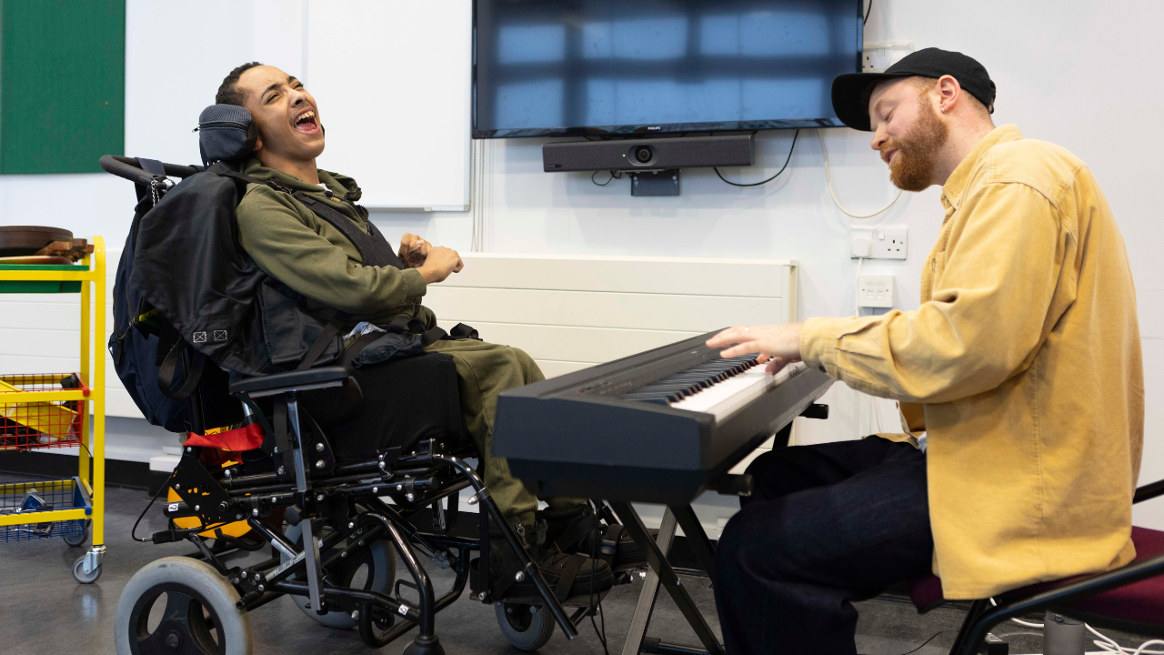 James, sat in his wheelchair, singing with music therapist Sam.