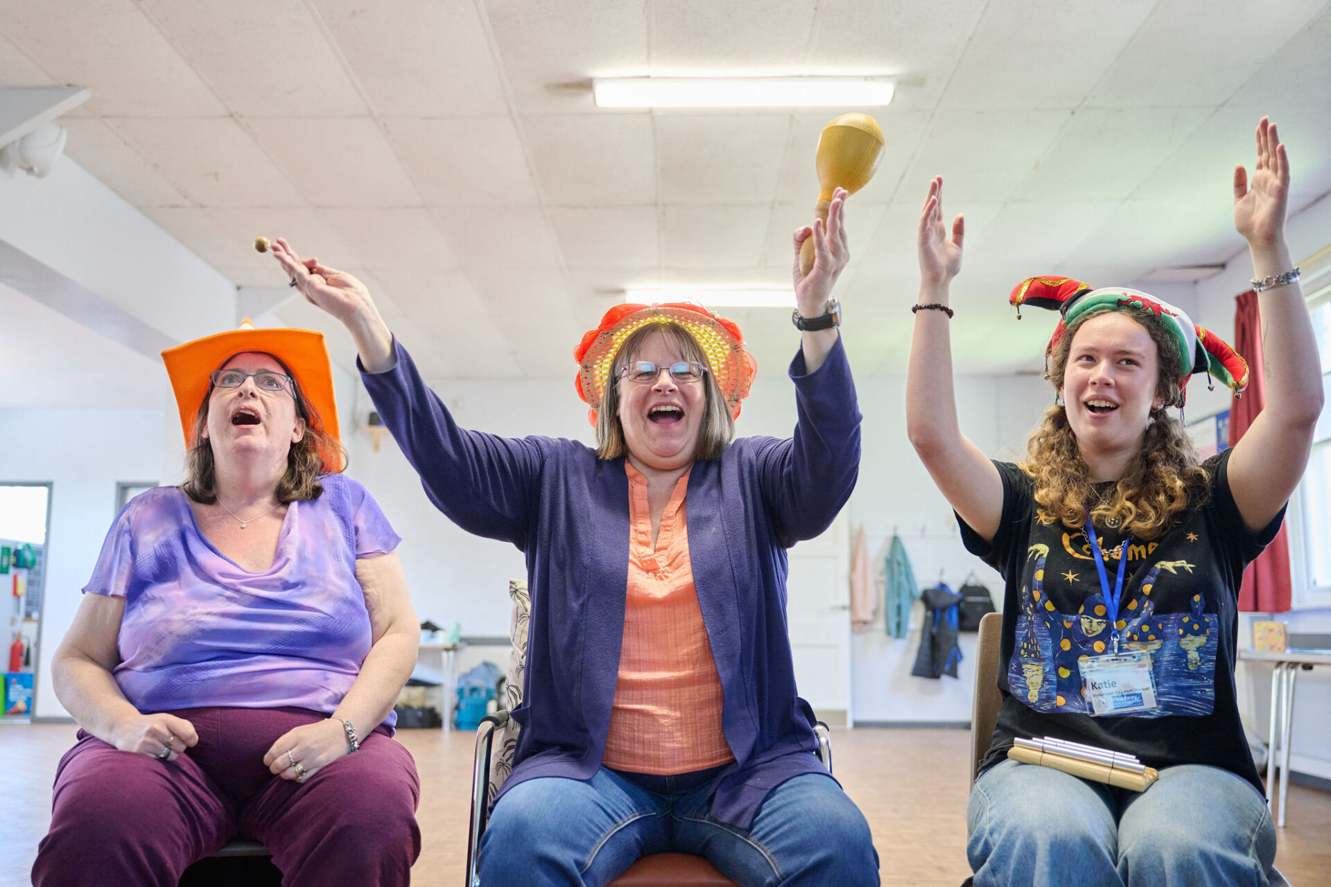 Three people sat in chairs playing musical instruments, and waving their arms in the air